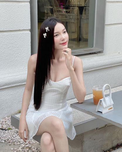 身穿白色蒲公英蕾絲迷你裙🌹倒數優惠至5月19日連身裙的女子坐在長凳上，桌上擺著飲料，微微微笑，頭髮上插著鮮花。