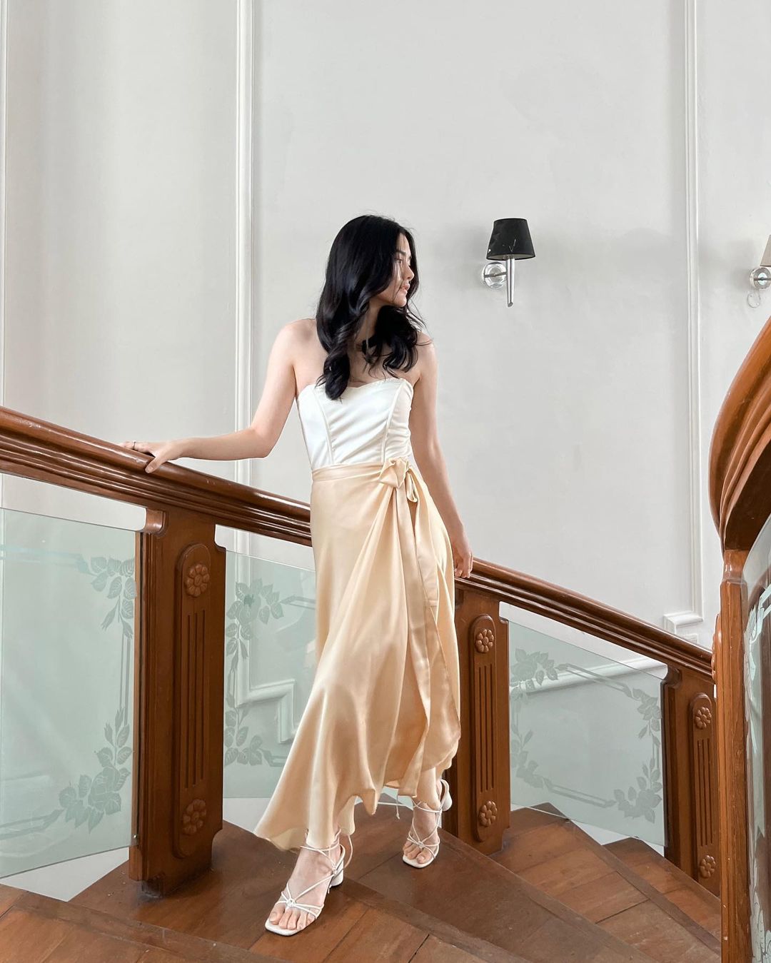 身穿優雅洋裝的女士穿著 the.lookbook.select 的芭蕾舞長裹身裙站在樓梯上。