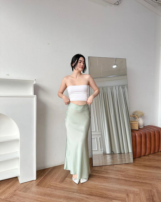 一位女士在明亮的房間裡穿著白色短上衣和 Sirene 長裙（來自 the.lookbook.select）擺姿勢。