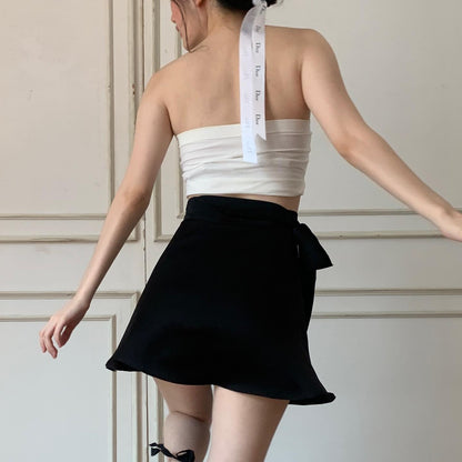 穿著黑色裙子和白色繃帶式上衣、脖子上掛著捲尺的人穿著 the.lookbook.select 的 Ballerina Satin 套裝。