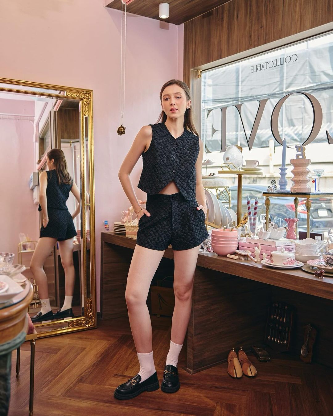 一位穿著來自 the.lookbook.select 的雛菊短褲套裝的女士站在一家精品店裡，一面大鏡子反射著她和室內裝飾。 🌹倒數優惠至5月19日
