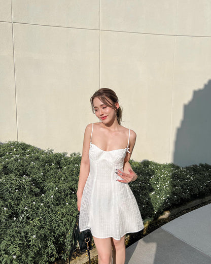一位穿著白色蒲公英蕾絲迷你裙🌹倒數優惠至5月19日 by the.lookbook.select 的年輕女子站在樹籬旁，在陽光照射下，帶著黑色小錢包，微笑著。