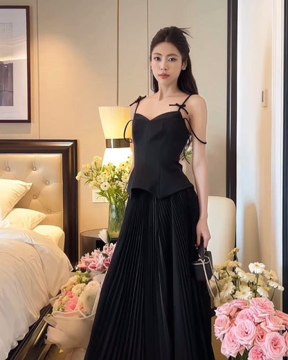 一位身穿來自lookbook.select的優雅黑色鬱金香裙套裝的女士站在臥室裡，周圍有一束粉紅玫瑰和花卉裝飾。