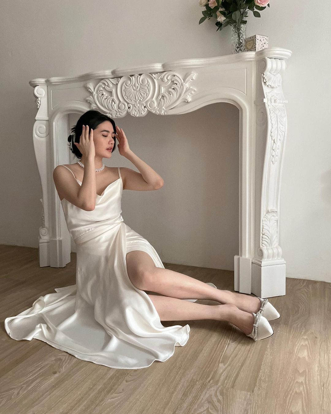 一位身穿白色洋裝的女士坐在華麗的畫框下，穿著 the.lookbook.select 的芭蕾舞長裹身裙，給人一種超現實、顛倒場景的錯覺。
