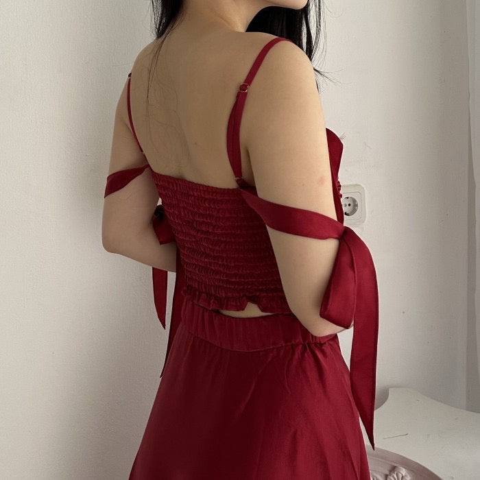 女人背對著鏡頭站著，身穿紅色連身裙，肩上有絲帶細節。