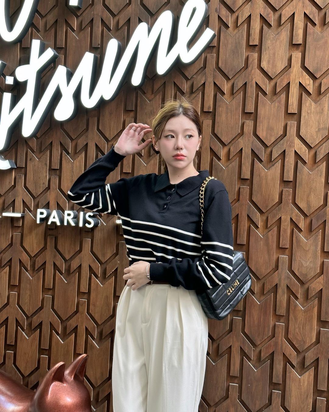 一位穿著 the.lookbook.select 出品的 Danielle 毛衣的女士正在巴黎標誌前擺姿勢拍照。