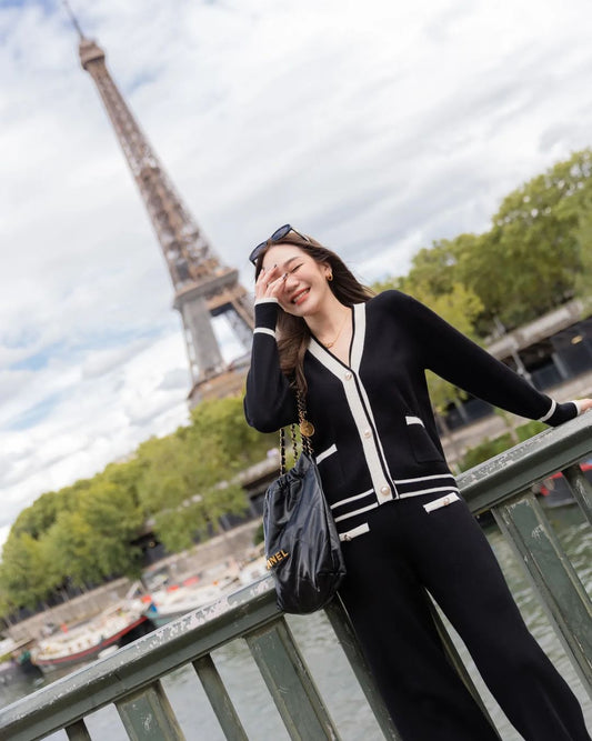 一位女士站在艾菲爾鐵塔前，身穿巴黎針織套裝布料製成的高架機場服裝，靈感源自 the.lookbook.select 的別緻黑白風格。