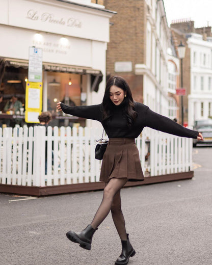 一位多才多藝的女性在倫敦繁華的街道上穿著高腰 the.lookbook.select 網球裙和黑色毛衣。