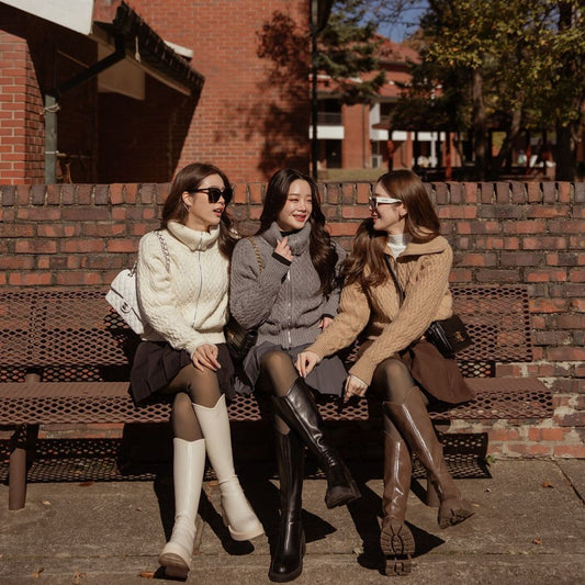 三位女士坐在長凳上，穿著 the.lookbook.select 的針織拉鍊毛衣享受陽光明媚的一天。