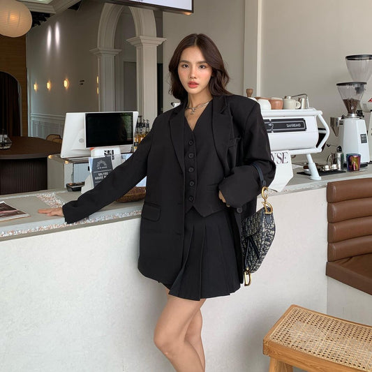 一位穿著 the.lookbook.select 週一套裝 3 件套（一件超大黑色西裝外套）的女士在咖啡店前擺姿勢。