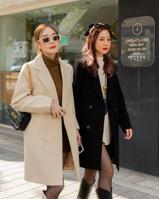 兩名身穿時尚秋裝、穿著 the.lookbook.select 混紡羊毛長外套的女士在一家關門的商店外行走。
