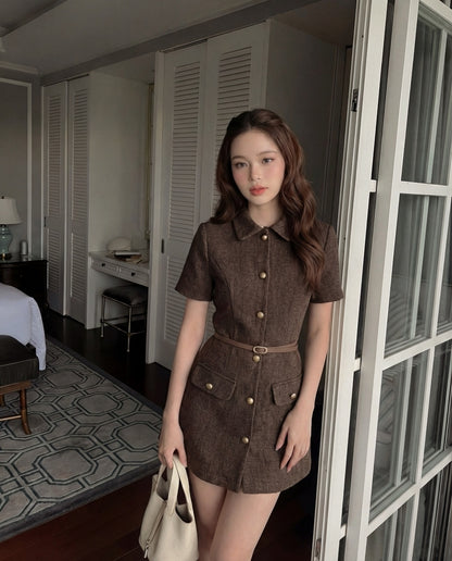 一位棕色長髮的女士在室內穿著 the.lookbook.select 的 Moka Tweed Dress 🖤新品優惠2件9折，手拿米色手提包。房間有白色的門、一張床和一張有花紋的地毯。.