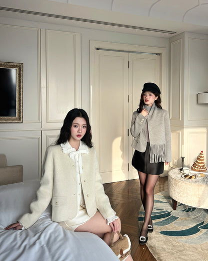 兩位女性在摩登的房間中擺姿勢，其中一位坐在奶油色的沙發上，另一位則站在.lookbook.select 的 Snow Wool Coat ❄️ 新品優惠，無領設計，搭配黑色短裙和貝雷帽。.