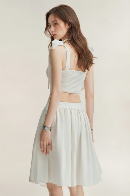 一位女性在淺色背景下側面，穿著 Jesse Midi Skirt 和白色無袖絲帶上衣 (the.lookbook.select)。.