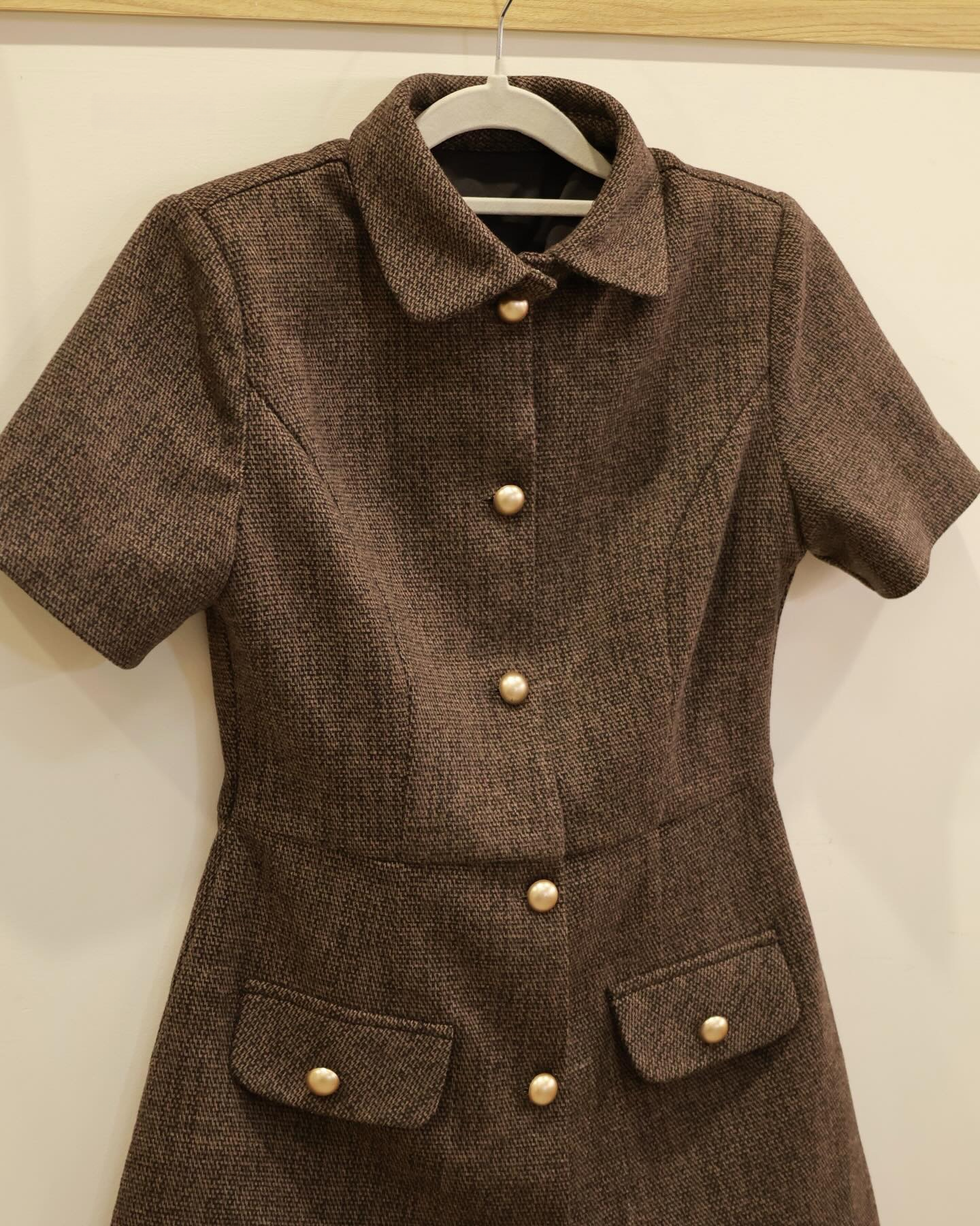 The.lookbook.select的Moka粗花呢連衣裙有短袖、領口、珍珠鈕扣和兩個腰部翻蓋口袋，圖中為棕色，配白色衣架。🖤新品優惠2件9折.