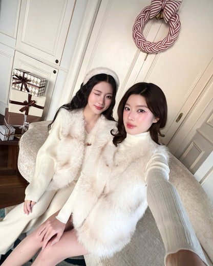 兩位女士穿著乳白色的搭配服飾，搭配來自 lookbook.select 的 La Neige Fur Vest ❄️ 新品優惠，讓她們坐在沙發上，一個眨眼睛，另一個則看著鏡頭，倍感溫暖。節日花圈和禮物讓溫馨的場景更加完美。.