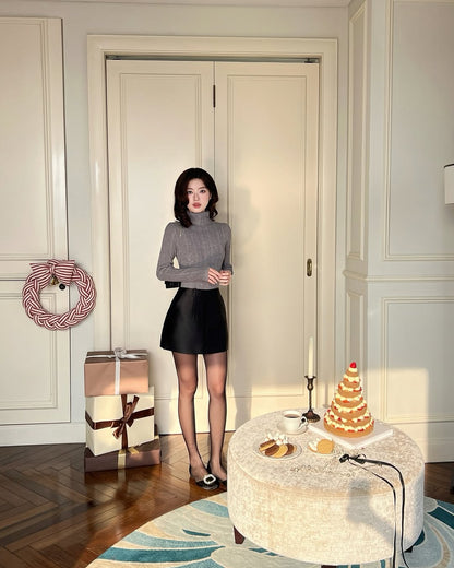 一位女士站在有禮物、花環和層疊甜點的節日室內，穿著.lookbook.select的Twinkle針織上衣❄️ 新品優惠，增添溫暖與時尚。.