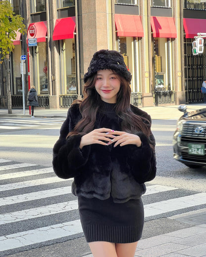 一位女士穿著 the.lookbook.select 的棉花糖皮草連帽大衣，站在市區的人行道上，身後建築物上的紅色遮陽篷清晰可見。.