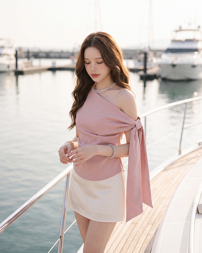 一名女子身穿由 .lookbook.select 推出的 Isola Drape Top，佇立於遊艇甲板上，背景可見遊艇與水面。.