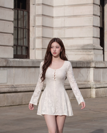 一位女士穿著the.lookbook.select的Verse Lace Minidress 🌙新品優惠2件9折，一件長袖白色蕾絲連身裙，走在戶外一棟有大窗戶的石造建築前。.