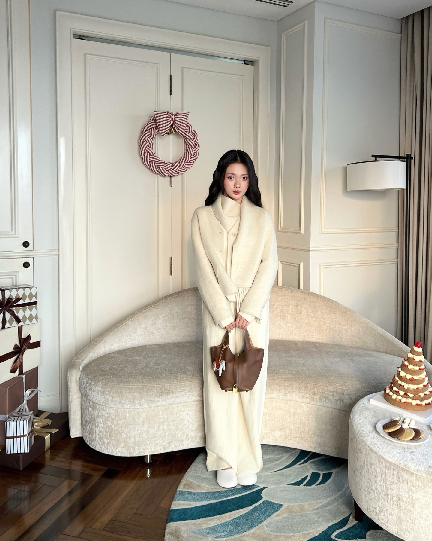 ❄️新品優惠 by the.lookbook.select 一位身穿乳白色 Snow Wool Coat 的女士站在米色弧形沙發前，手持棕色袋子。節日裝飾品和禮物點亮了現代客廳。.