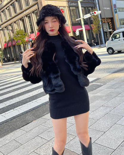 一位女士穿著the.lookbook.select的棉花糖皮草大衣（附帽子），站在城市的人行道上，背景是建築物、車輛和交通燈。.