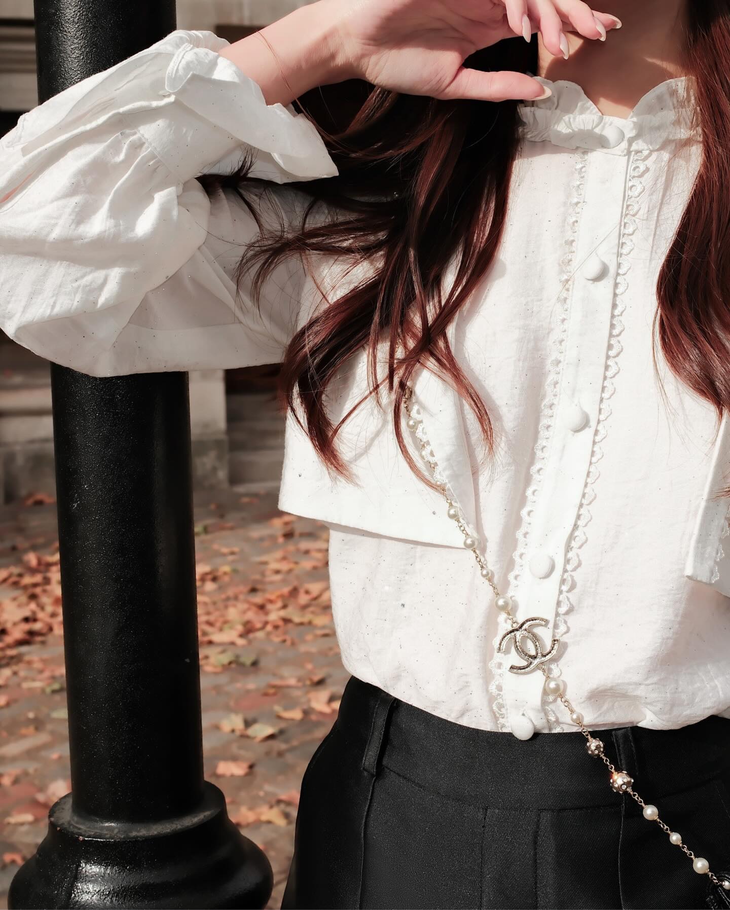 在.lookbook.select Hazel White Shirt 🖤新品優惠至 12 月 5 日，一個人在戶外散發法式魅力，造型搭配荷葉邊細節、黑色褲子、Chanel 鏈條手袋，以及散落在腳邊的落葉。.