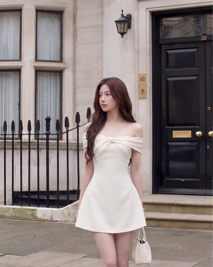 一位女士穿著 the.lookbook.select 的 Grandeur Twist 迷你裙，站在一棟有大窗戶和黑色大門的建築物前的人行道上。.