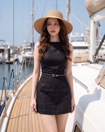 一名身穿.lookbook.select 卡普里系帶迷你洋裝、頭戴寬簷帽的女子，站在遊艇甲板上，背景中可見其他船隻與遊艇碼頭。.