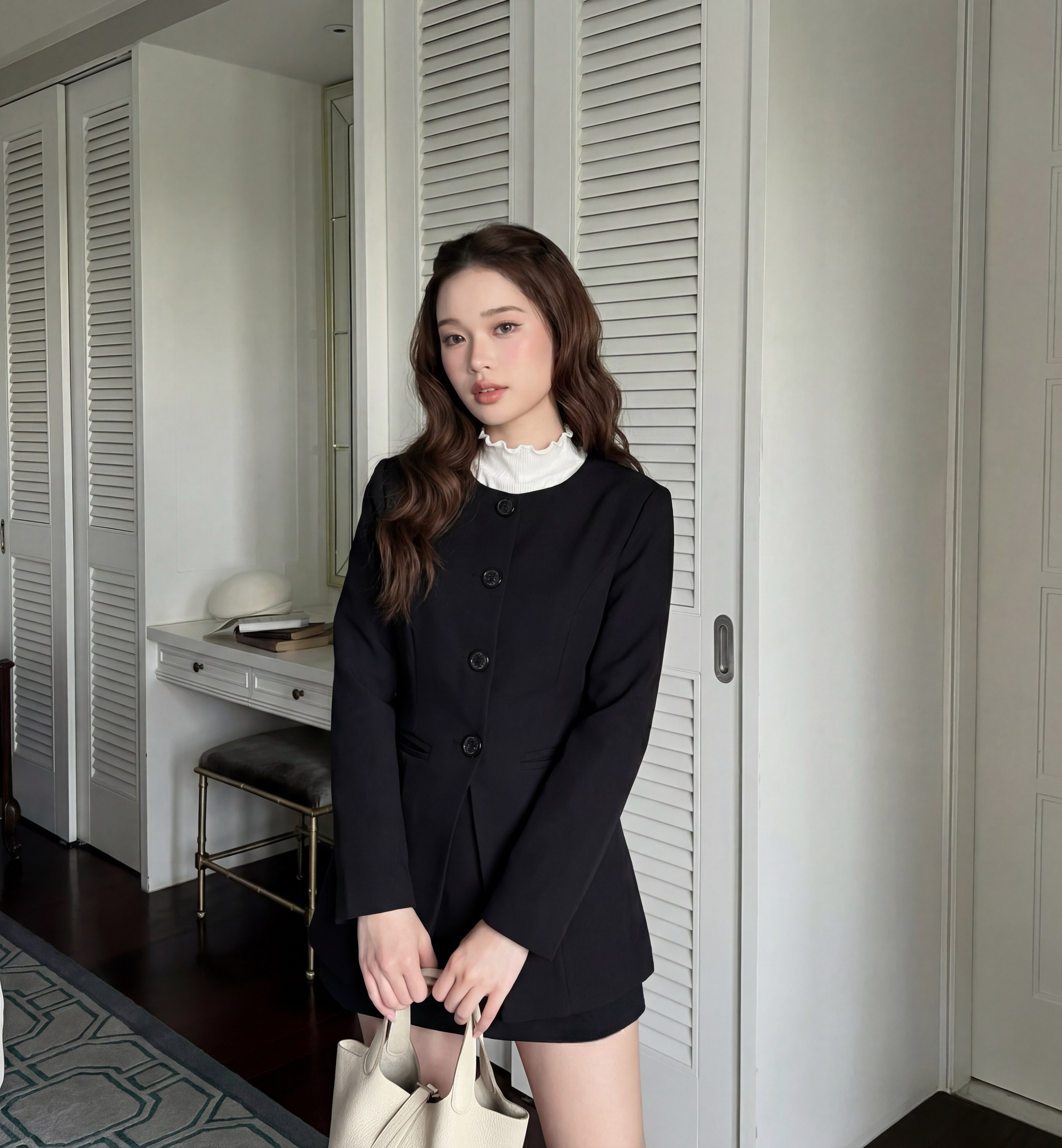 The.lookbook.select的All Black Set (Coat & Pants)🖤新品優惠2件9折，採用白色褶邊領口，手持米色包包，站在白色板門和帶帽子的辦公桌旁。.