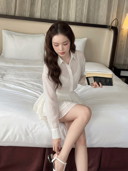 穿著 the.lookbook.select 的 Morning Mist Ruffle Set (Top & Skirt) 的女性坐在床上，一手拿著一本打開的書，一手系著一雙白色涼鞋。.
