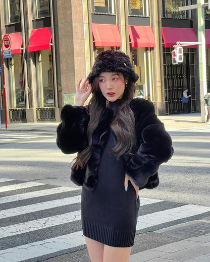 一位女士穿著 the.lookbook.select 的棉花糖皮草大衣搭配帽子，站在市區的人行道上，背景是建築物。.