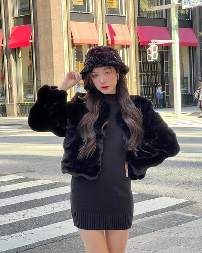 一位女士穿著 the.lookbook.select 的棉花糖毛皮大衣連帽子，站在城市的人行道上，靠近紅色遮陽篷，一身黑衣。.