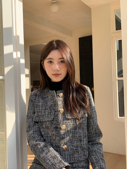 一位身著 the.lookbook.select 出品的 This Girl Tweed Set 的女子站在室內門口附近，面朝前方。.