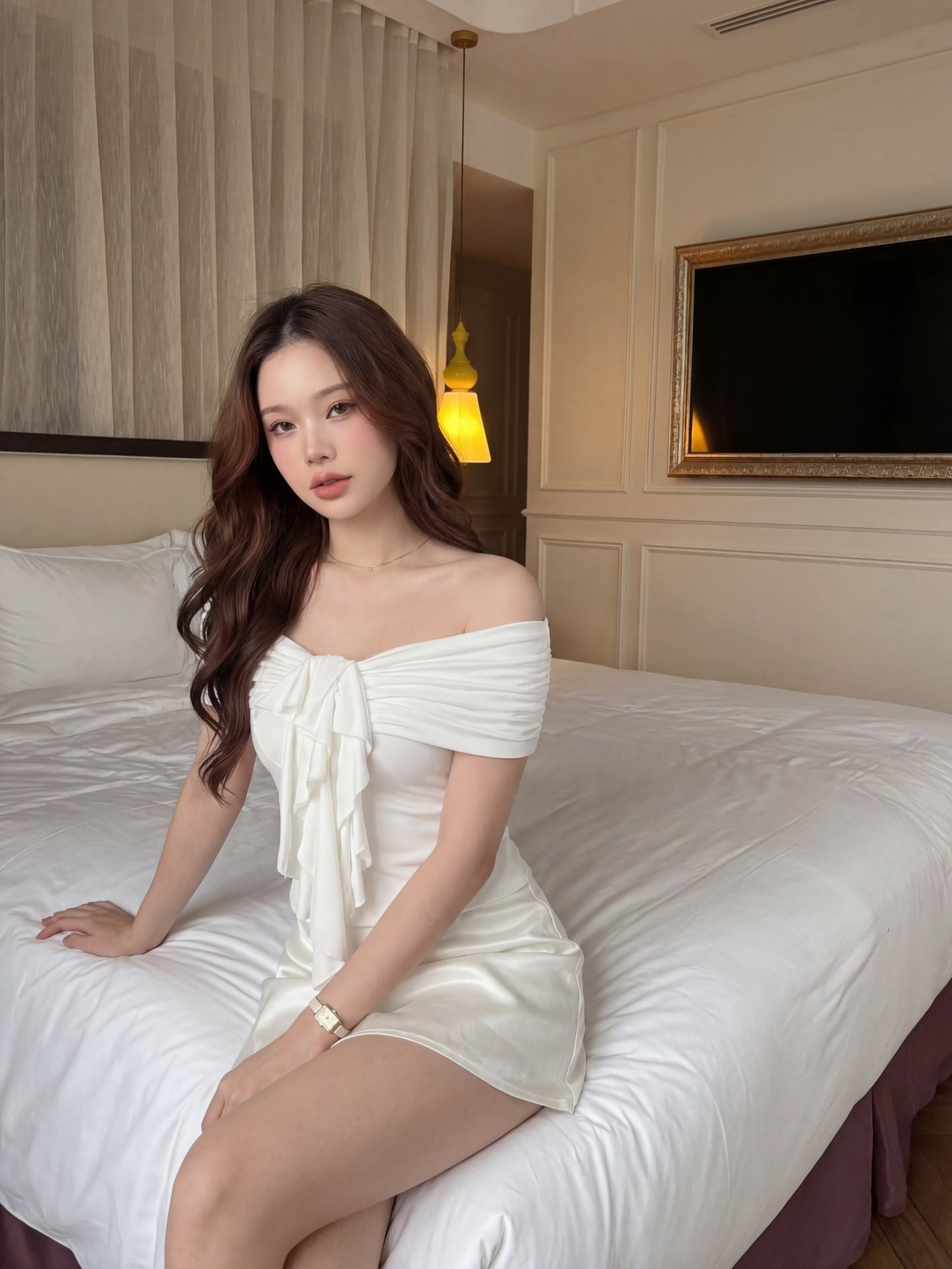 一位女士身穿 the.lookbook.select 的 Petal Bardot Top 🖤新品優惠2件9折，坐在光線柔和的中性色調臥室中整齊的床邊。.