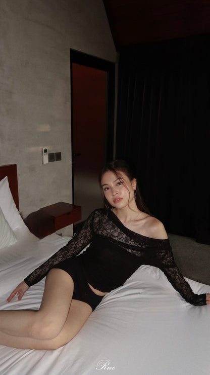 一位年輕女子穿著 the.lookbook.select 的蕾絲露肩上衣在飯店房間的床上擺姿勢。