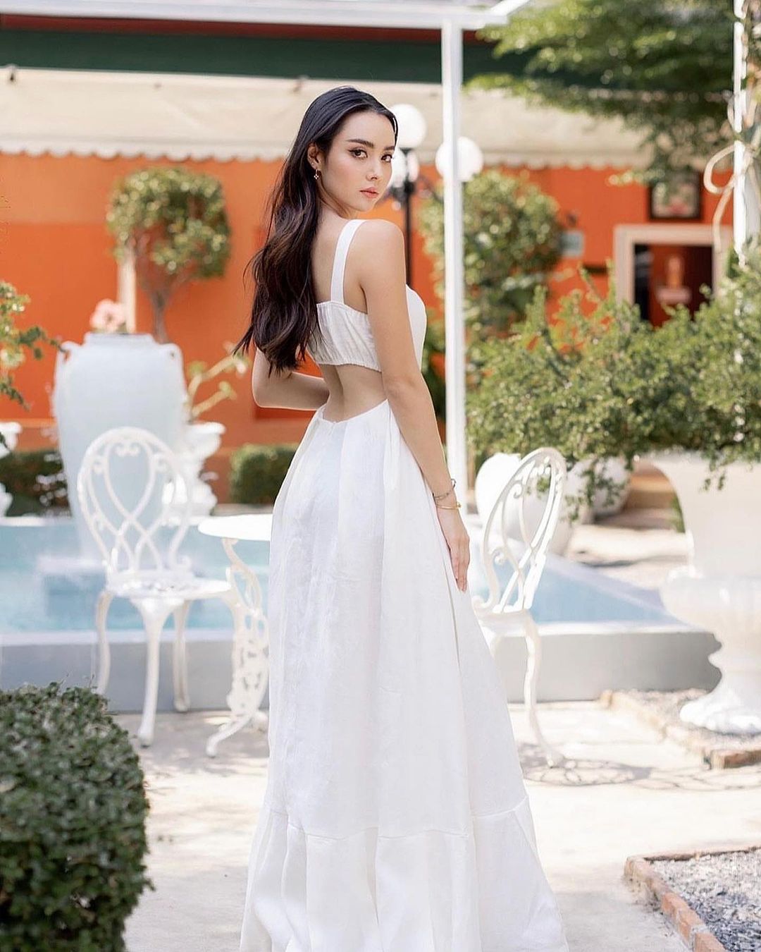 一位夢幻般的女士穿著 the.lookbook.select 的白色亞麻 Leeann 長裙，在花園裡擺出公主般的姿勢。