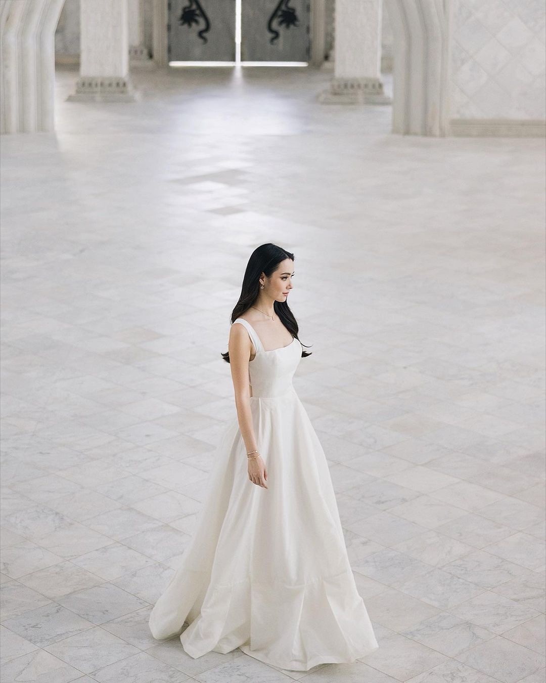 一位夢幻般的新娘穿著 the.lookbook.select 的 Leeann 長裙站在空蕩蕩的房間裡。